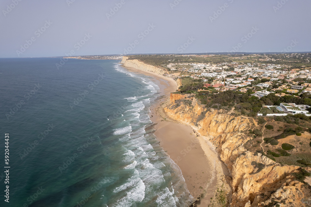 Aerial of Lagos Portugal views of Praia do Camilo and lighthouse at sunrise. Beautiful natural beaches and cliffs