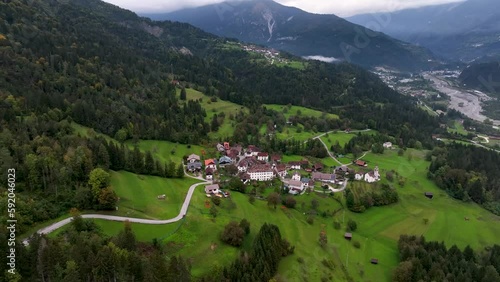 OVARO MIONE, ITALY - APRIL, 2023: Aerial drone view of a valley in the morning with clouds. Small mauntain village Mione with beautiful houses on the green slopes of the Italian Alps. photo