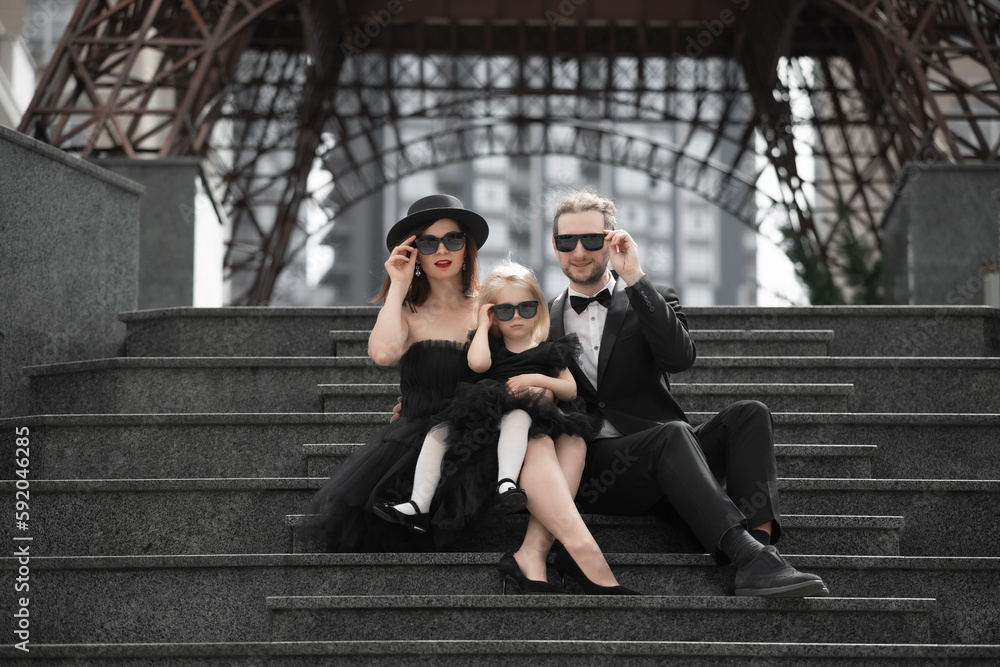 Family of three in black outfits and glasses
