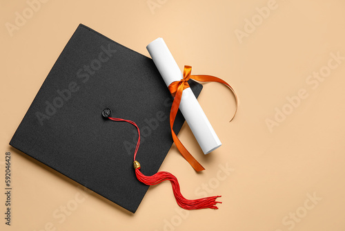 Diploma with red ribbon and graduation hat on beige background