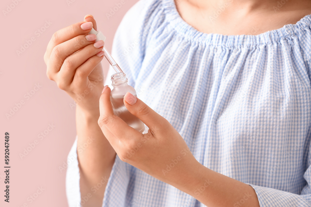 Woman with bottle of cuticle oil near color wall Woman with bottle of cuticle oil near color wall