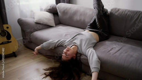 Young couple laying on the sofa with heads upside down, having fun, relaxing