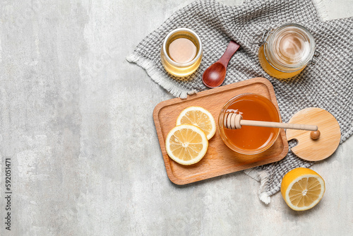 Jars of sweet honey and lemon on grey background