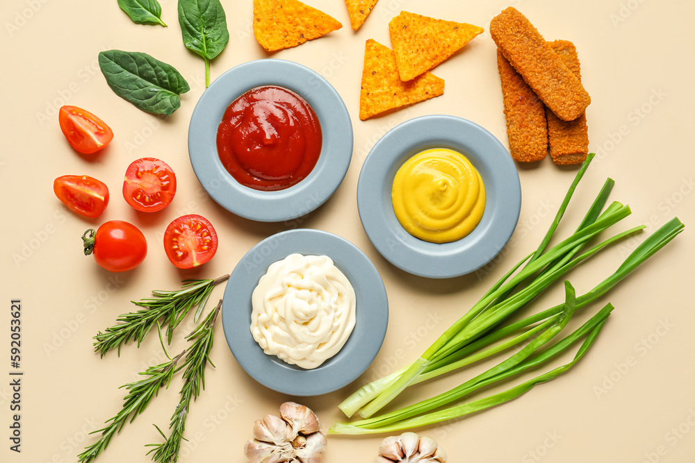 Plates with different sauces, snacks and vegetables on beige background Plates with different sauces, snacks and vegetables on beige background