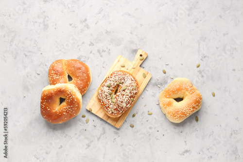 Wooden board of tasty bagels with sesame and pumpkin seeds on grunge background