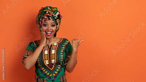 Amazed black woman in african clothes showing copy space
