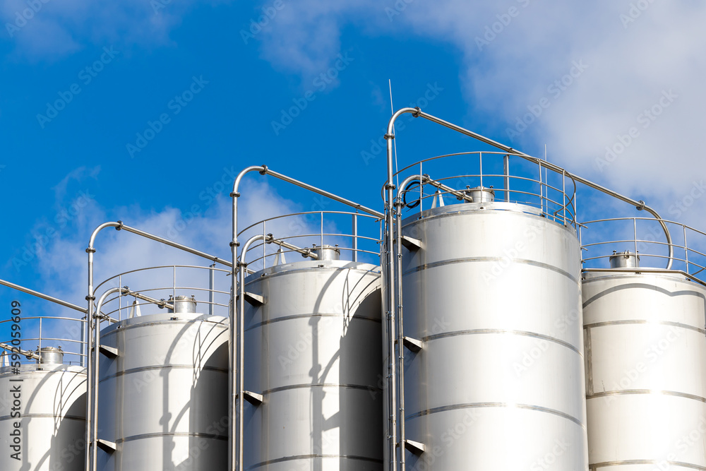 Stainless steel silos against the blue sky. Warehouses for storage of plastics and bulk grains. Stainless steel silos against the blue sky. Warehouses for storage of plastics and bulk grains.