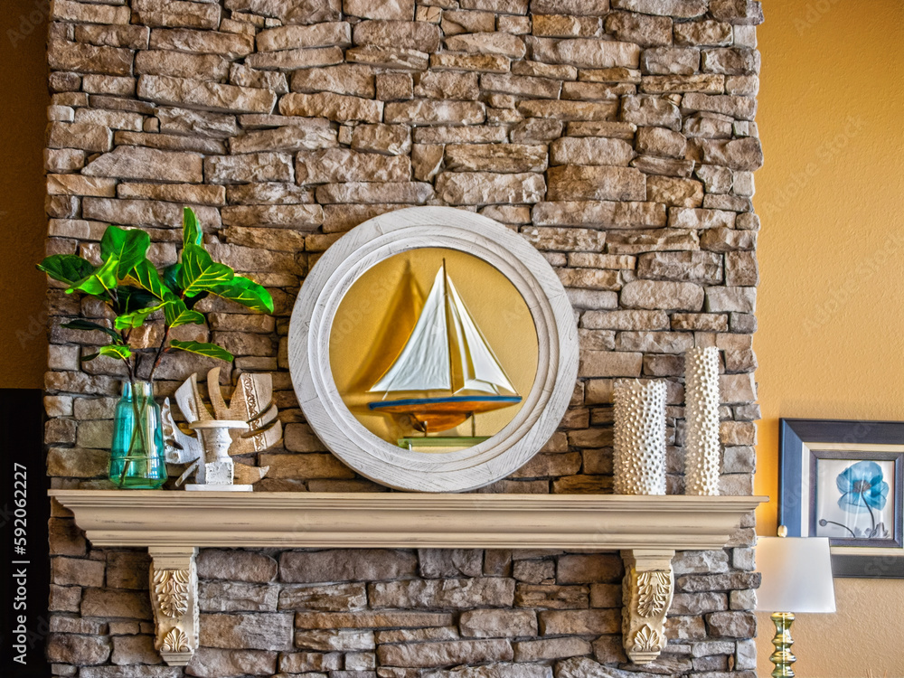 Mantlepiece on rock fireplace decorated with candles, fig leaf in vase and mirror reflecting a model ship Mantlepiece on rock fireplace decorated with candles, fig leaf in vase and mirror reflecting a model ship