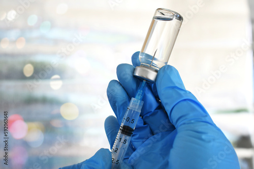 Medical personnel filling a syringe needle with generic vaccine booster from vial
