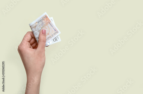 Woman with pound sterling banknotes on beige background