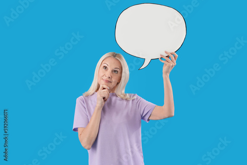 Thoughtful mature woman with blank speech bubble on blue background