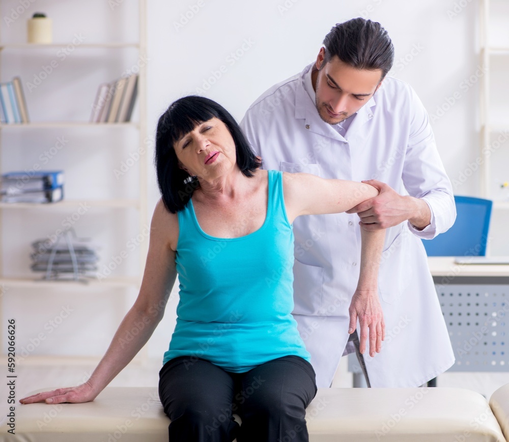 Fototapeta premium Young male doctor examining old female patient