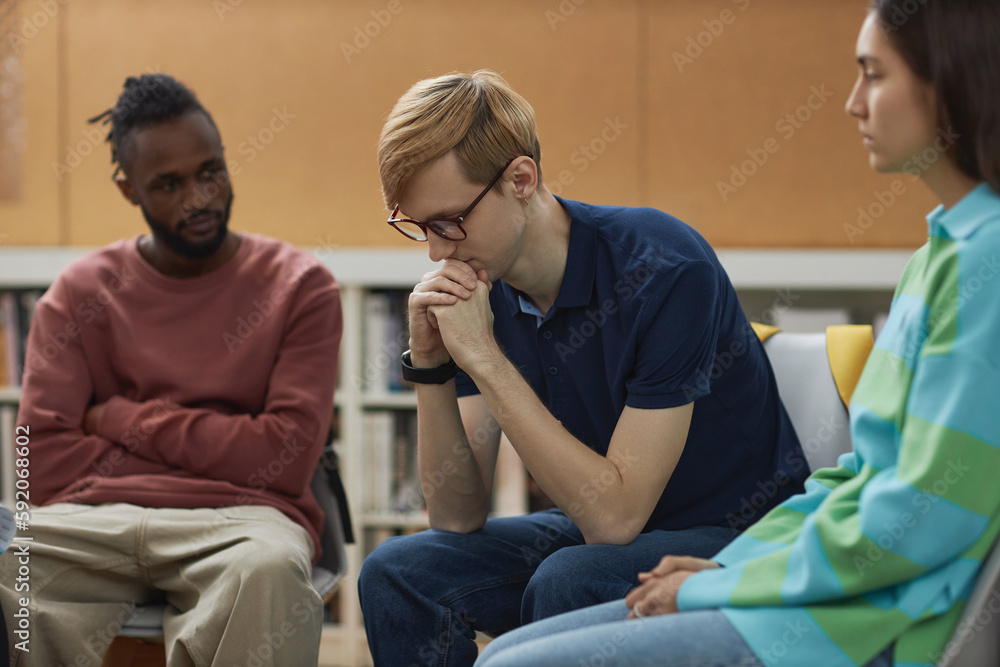 Obraz premium Portrait of troubled young man in support group circle sharing his story