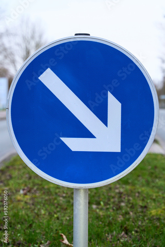 The traffic sign mandatory passing, right past, shows the lane to drive to. Street sign for the orientation of road users. Close up of a road sign.