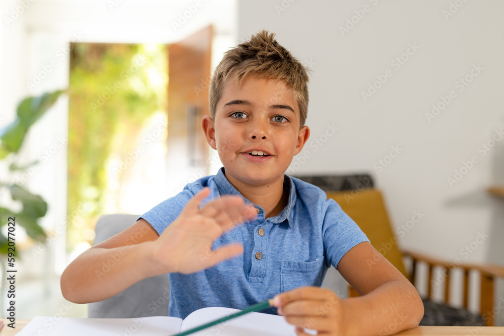 Portrait of caucasian cute boy with book sitting against white wall at home, copy space Portrait of caucasian cute boy with book sitting against white wall at home, copy space