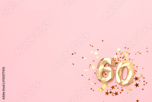Fotografering Gold colored number sixty and glowing stars confetti on a pink background