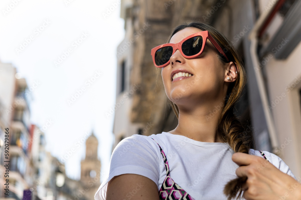 Portrait of pretty caucasian woman posing with pink square prescription sunglasses on the street. Glasses promotion. Glasses models. Concept of promotion and sale of optical glasses. Portrait of pretty caucasian woman posing with pink square prescription sunglasses on the street. Glasses promotion. Glasses models. Concept of promotion and sale of optical glasses.