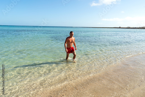 Attractive muscular athletic man in the ocean. Summer vacation. Sunny day.