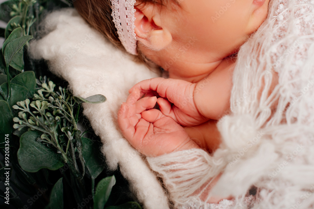 Newborn baby sleeping covered in white blanket in a selective focus