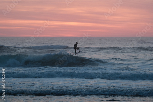 silhouette of a surfer surfing on the beach during sunset