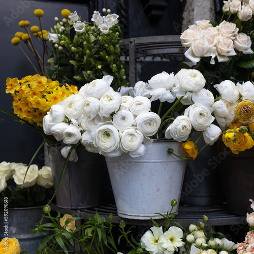 Large armfuls of pink roses, yellow and white ranunculus, bluebell, freesia, daffodils in metal pails for sale photo