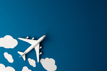 Close up of airplane model with clouds on blue background with copy space