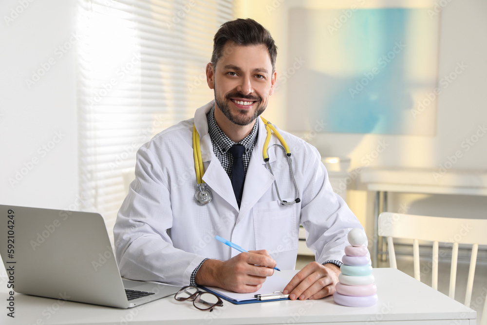 Pediatrician with stethoscope at table in clinic Pediatrician with stethoscope at table in clinic
