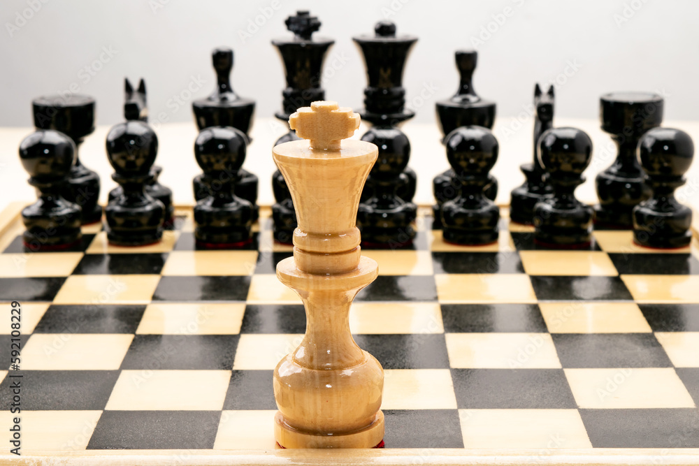 White chess king alone against black pieces in the background. on white background