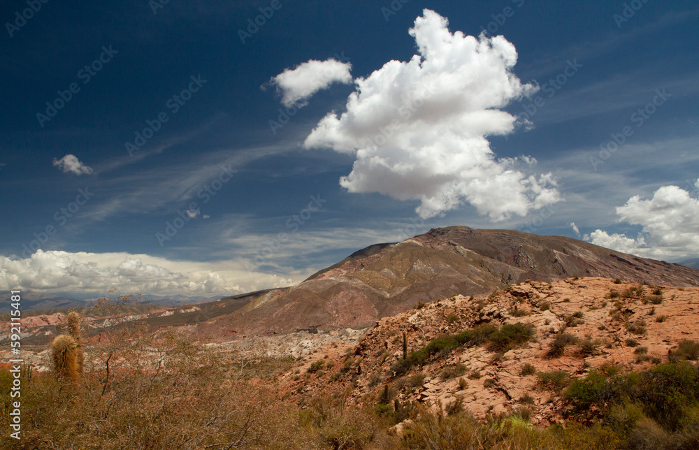 The arid desert. View of the rocky valley and colorful mountains under a magical sky with clouds.	
