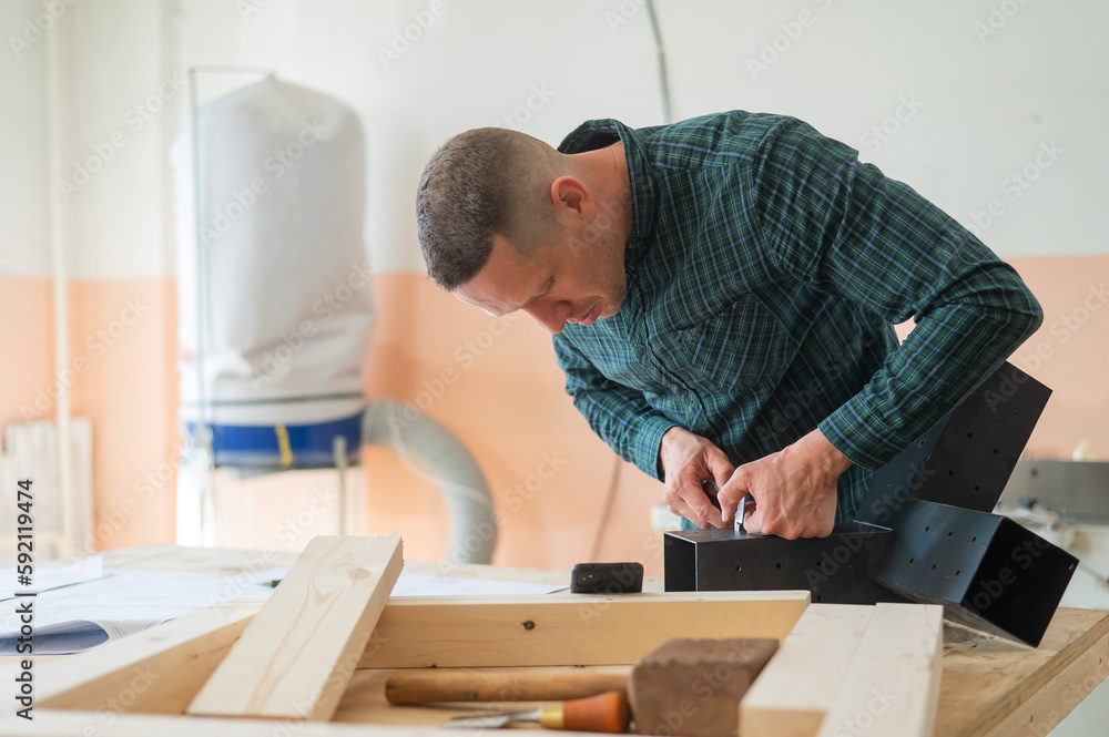 Carpenter measures a metal connector for wooden parts. Carpenter measures a metal connector for wooden parts.