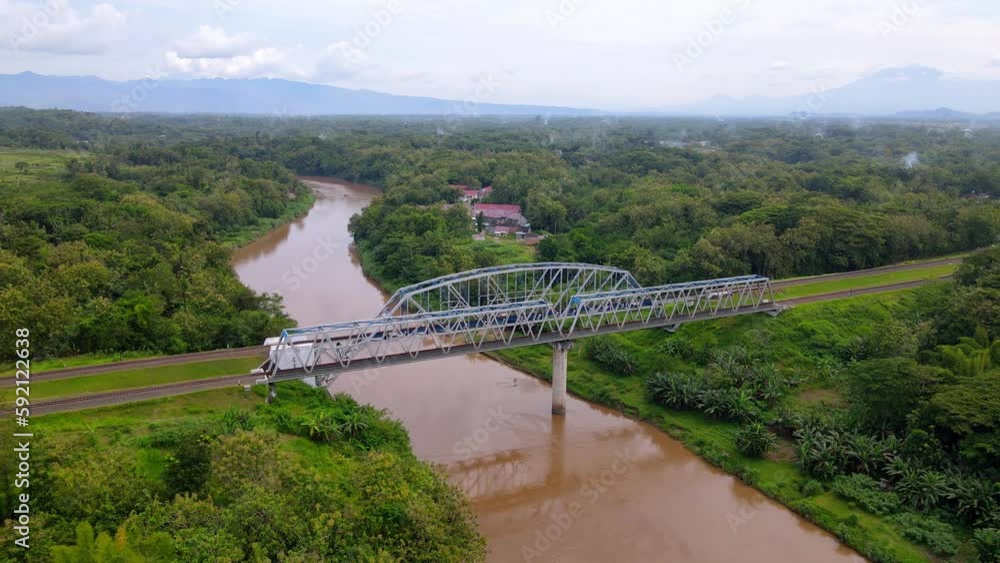 Drone view orbiting train track bridge over river with brown water, Indonesia Drone view orbiting train track bridge over river with brown water, Indonesia