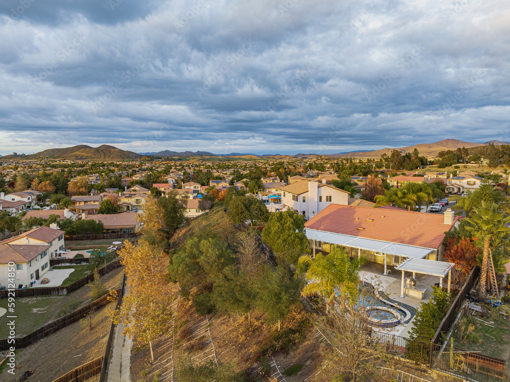Obraz premium Aerial view of backyard with pool on a cul de sac street surrounded by luxury single family homes rolling hills in new residential West Coast USA real estate suburban neighborhood dramatic sunset sky