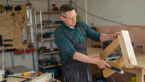 The carpenter shakes off sawdust from a wooden product. 