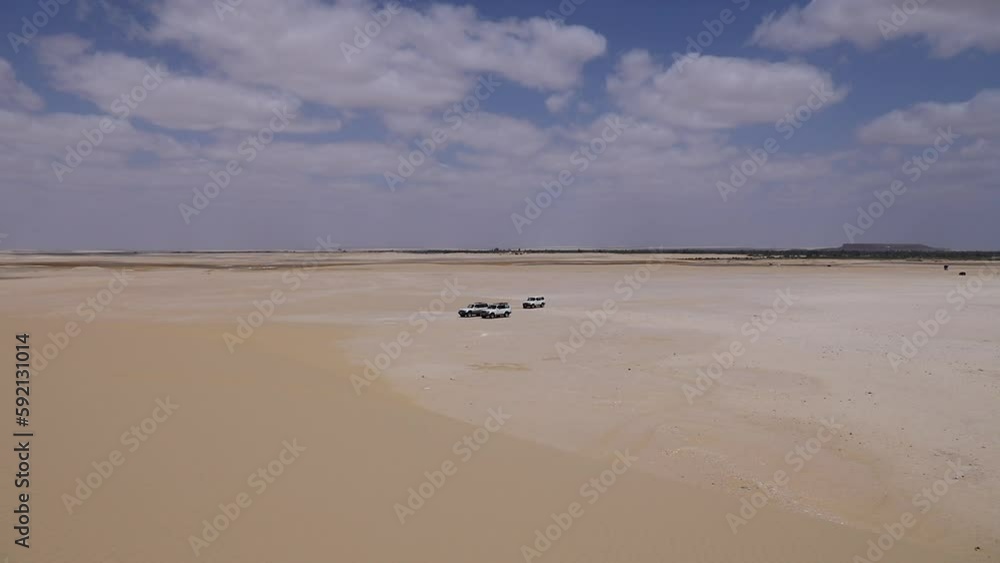 Cars parks on the sand under a cloudy sky in the desert - fixed camera Cars parks on the sand under a cloudy sky in the desert - fixed camera