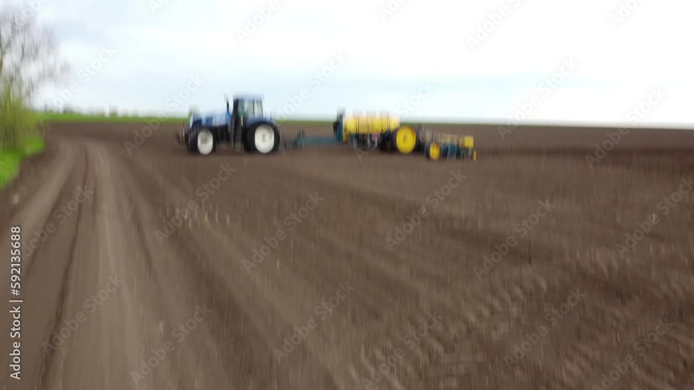 Blue tractor with yellow seeder working on the field in Ukraine OA Blue tractor with yellow seeder working on the field in Ukraine OA