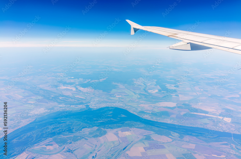 Aerial view from airplane window above green ground. View from the airplane window with beautiful clouds at sunrise Aerial view from airplane window above green ground. View from the airplane window with beautiful clouds at sunrise