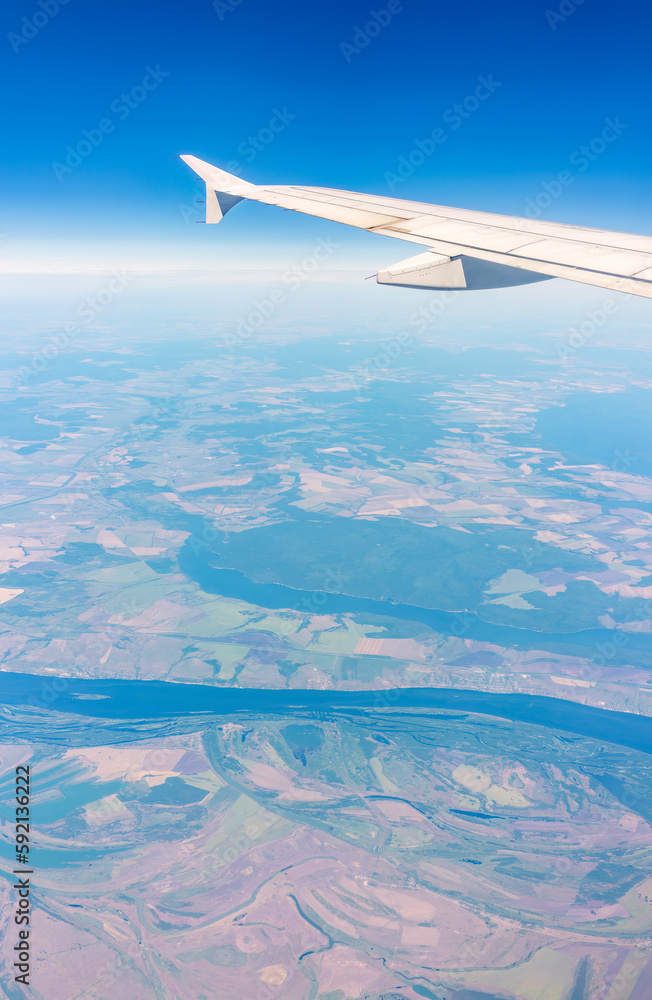 Aerial view from airplane window above green ground. View from the airplane window with beautiful clouds at sunrise Aerial view from airplane window above green ground. View from the airplane window with beautiful clouds at sunrise