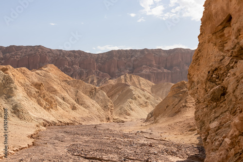 Rear view of man hiking in golden Canyon with scenic view of colorful geology of multi hued Amargosa Chaos rock formations, Death Valley National Park, California, USA. Barren Artist Palette landscape photo