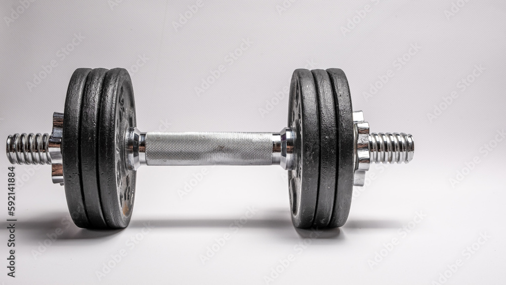 Iron dumbbell with pancakes on a white background. Sports with weights. Iron dumbbell with pancakes on a white background. Sports with weights.
