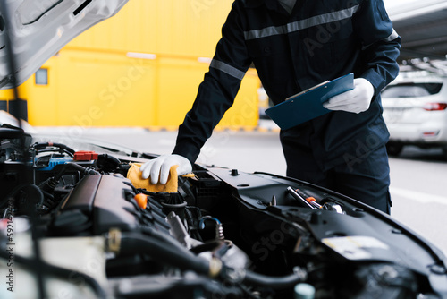 Quadro su tela Automobile mechanic repairman checking a car engine by inspecting and writing to the clipboard the checklist for repair machine and car service for maintenance and maintenance check concept
