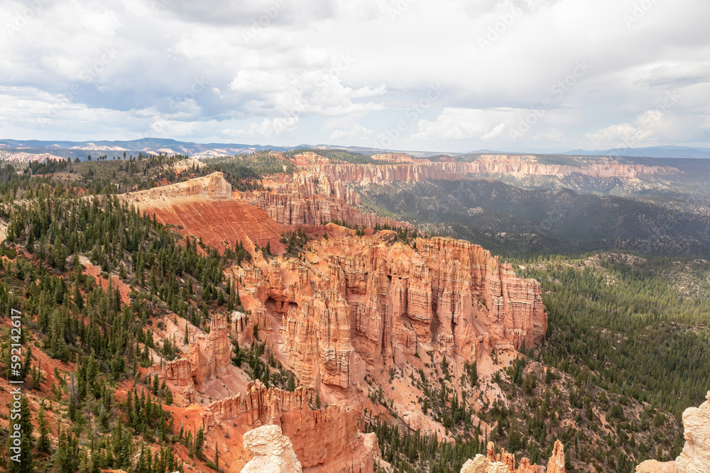 Scenic view of massive hoodoo sandstone rock formation towers on Navajo hiking trail in Bryce Canyon National Park, Utah, USA. Pine tree forest surrounded by natural amphitheatre on sunny summer day