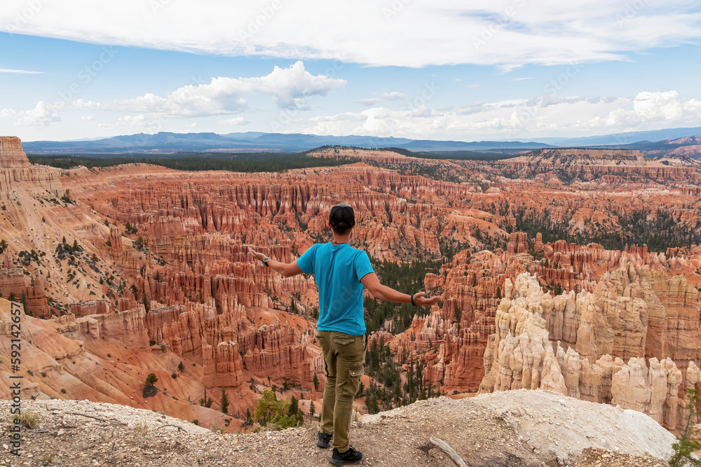 Rear view of man spreading his arms with aerial view of massive hoodoo sandstone rock formations, Bryce Canyon National Park, Utah, USA. Natural amphitheatre sculpted red rocks of Claron Formation