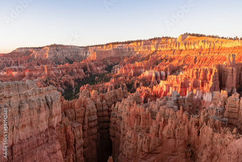 Aerial sunrise view of impressive hoodoo sandstone rock formations in Bryce Canyon National Park, Utah, USA. First morning sun rays touching on natural unique amphitheatre sculpted from red rocks