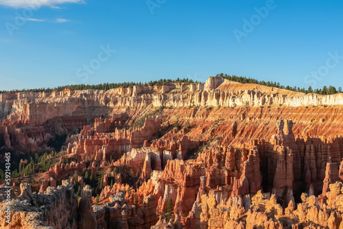 Aerial scenic morning sunrise view of hoodoo sandstone rock formations on Navajo Rim hiking trail in Bryce Canyon National Park, Utah, USA. Golden hour colored natural amphitheatre in barren landscape