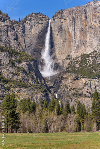 Yosemite Falls - A vertical full view of spectacular Yosemite Falls roaring off steep and solid granite cliff wall on a sunny Spring day. Yosemite National Park, California, USA.