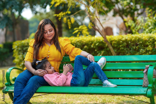 Indian little girl using smartphone with her mother at park