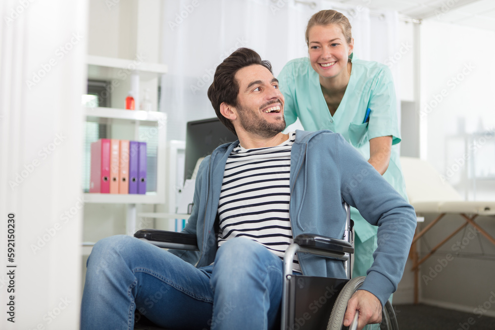 smiling female nurse pushing disabled patient sitting on wheelchair