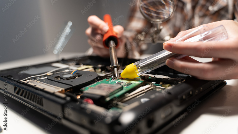 Naklejka premium the master solders the board with a soldering iron