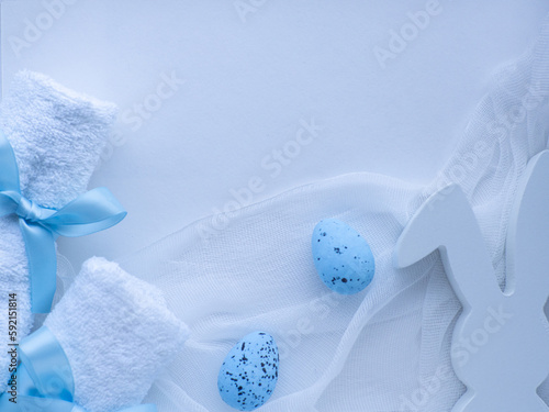 Wellness Easter concept. Set white towels tied with a ribbon in a bow, blue eggs, bunny and copy space. White Easter card. Rolled towels in spa salon. Hygiene and spa, relaxation as gift for holidays.