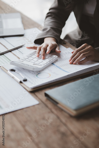 Businessman using a calculator to calculate numbers on a company's financial documents, she is analyzing historical financial data to plan how to grow the company. Financial concept.